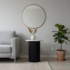 Modern living room with a round mirror, black side table, and potted plant.