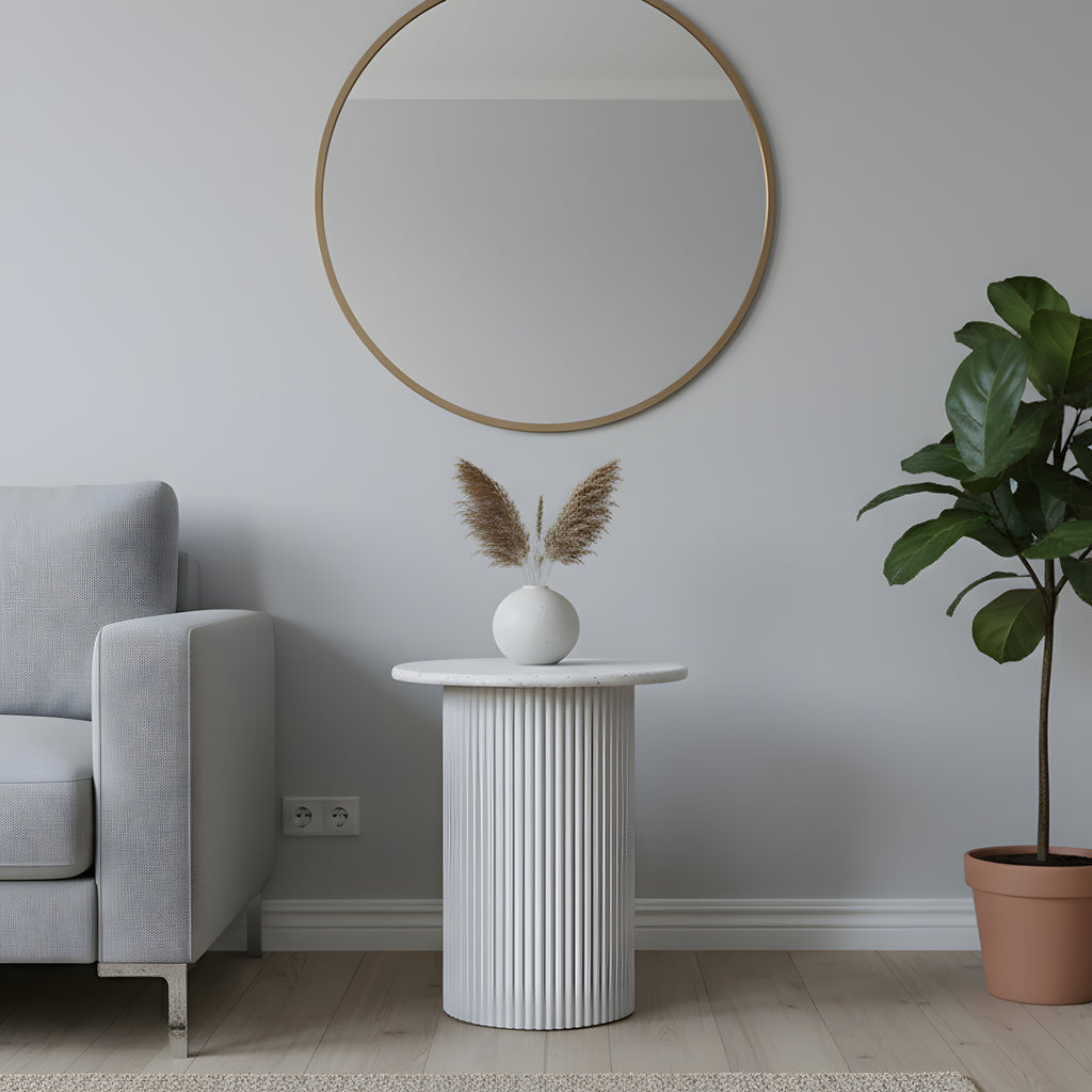 Modern living room with a round mirror, white side table, and potted plant.